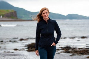 A woman walking toward the camera on near a beach