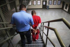 Guard escorting ICE detainee.