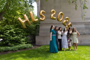 A group of six women pose under golden Harvard Law School balloons.